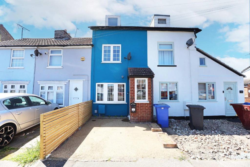 une maison bleue et blanche avec une voiture garée devant dans l'établissement 19th-century fishermans cottage, à Corton