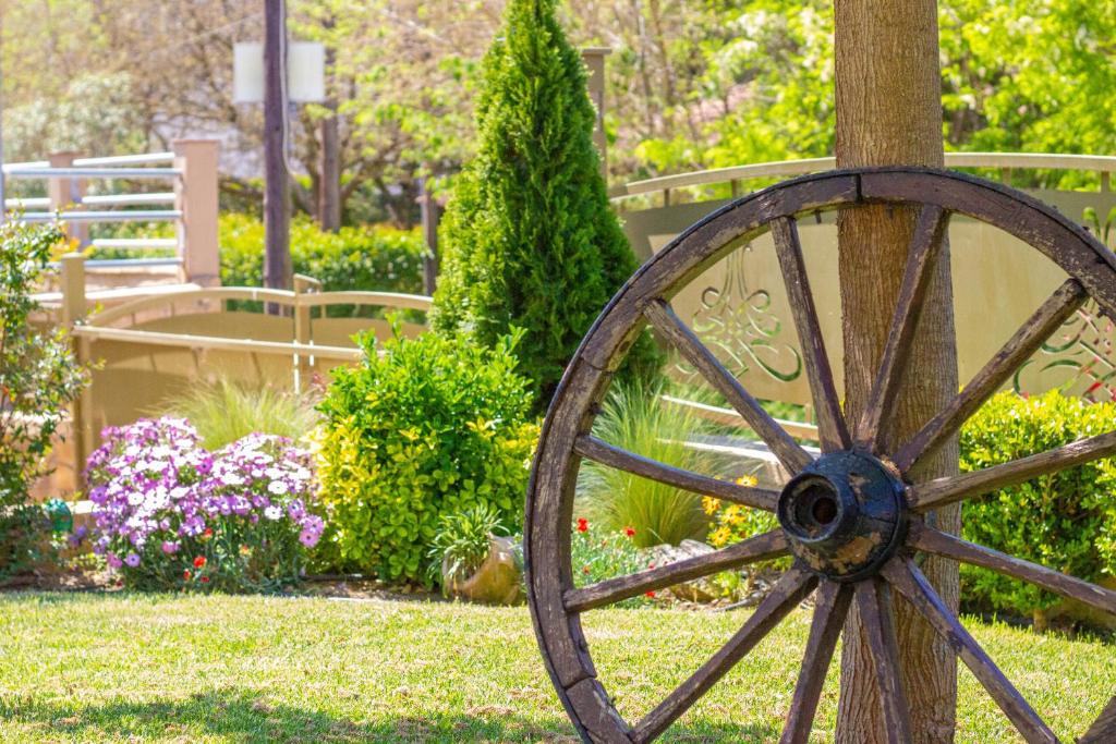 a wooden wagon wheel sitting next to a tree at Annis House in Epanomi