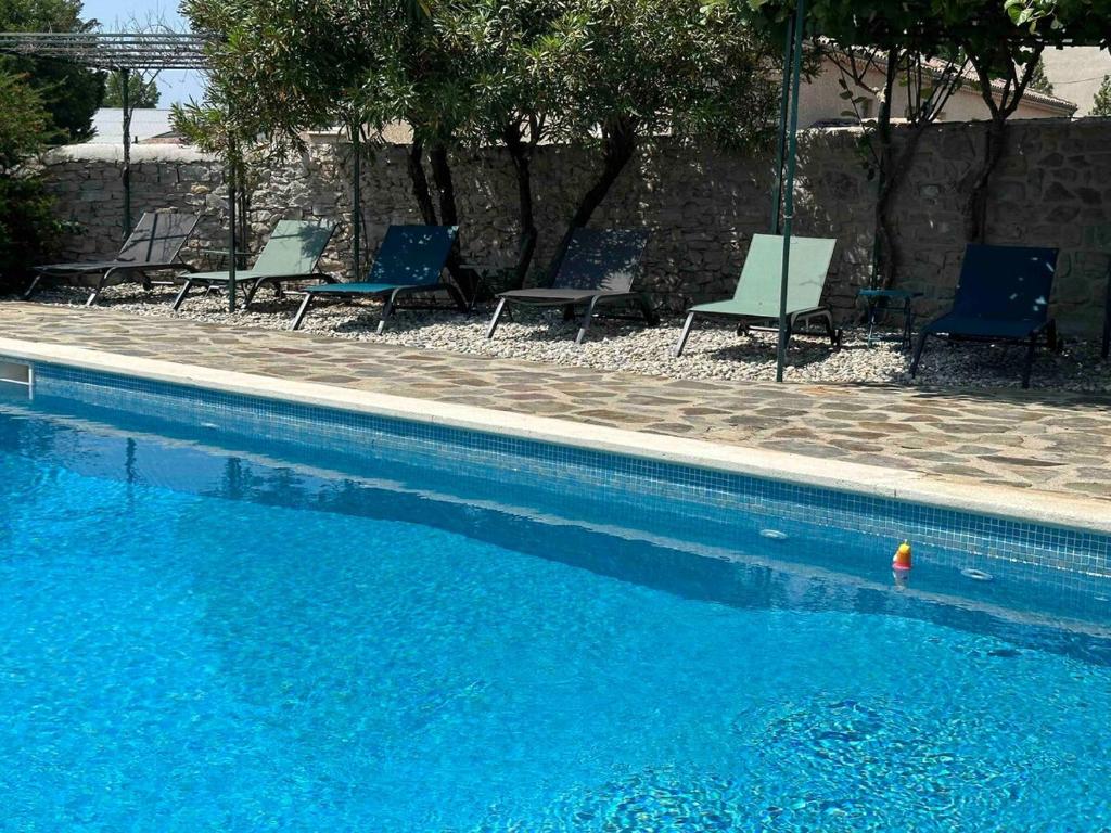 une piscine avec des chaises bleues et une piscine bleue dans l'établissement La Picholine, à Aubenas