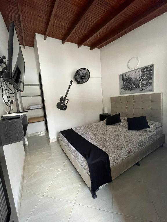 a bedroom with a bed and a guitar on the wall at Hotel San Pablo boutique H9 in Medellín