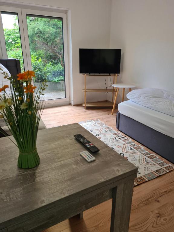 a room with a table with a vase of flowers on it at WellandHome Aalen - Business Apartment - 4 single beds in Aalen