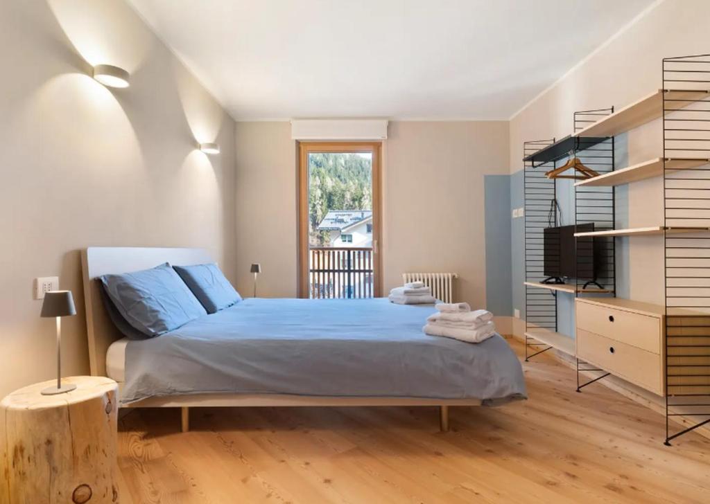 a bedroom with a bed with blue sheets and a window at Palazzo Righi - App Blu in Carisolo