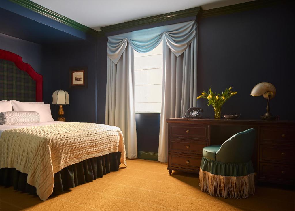 a bedroom with a bed and a chair and a window at Portrush Adelphi in Portrush