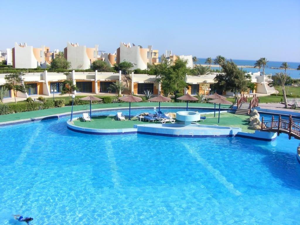 拉斯苏德尔فيلا هولداي فانتازيا Sea VIEW的一座带蓝色水和遮阳伞的大型游泳池