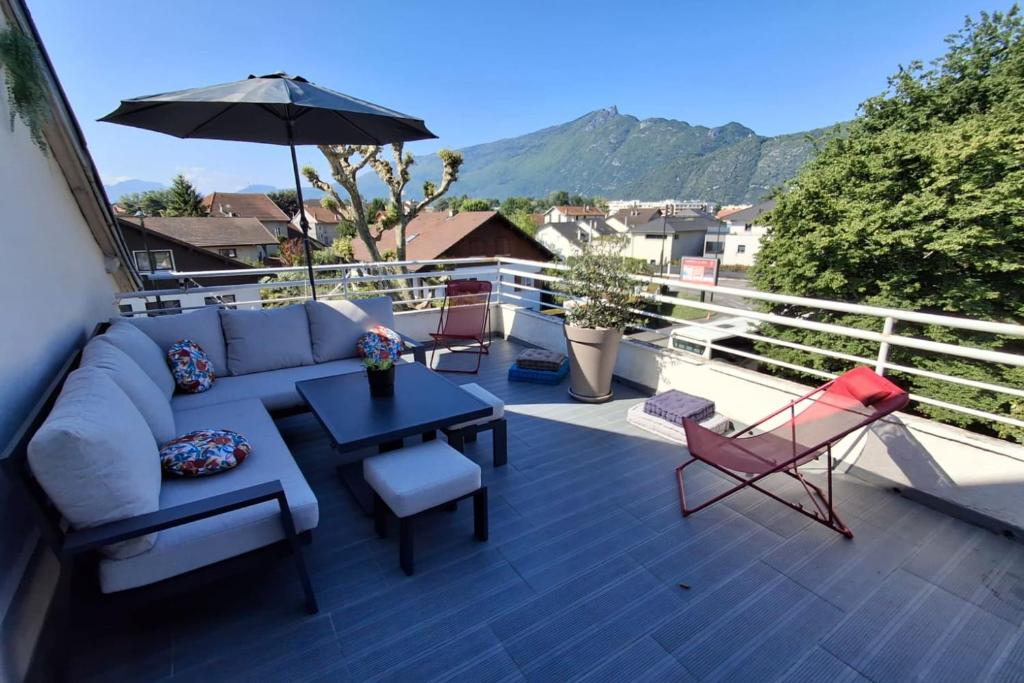 une terrasse avec un canapé, des chaises et un parasol dans l'établissement Le Balcon du Port- private parking, à Aix-les-Bains
