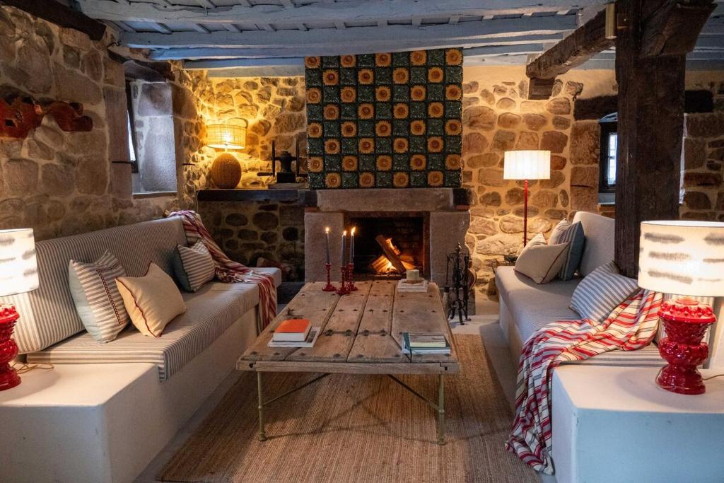 ein Wohnzimmer mit zwei Sofas und einem Kamin in der Unterkunft Casa Rural Boutique cerca de Comillas in Cos
