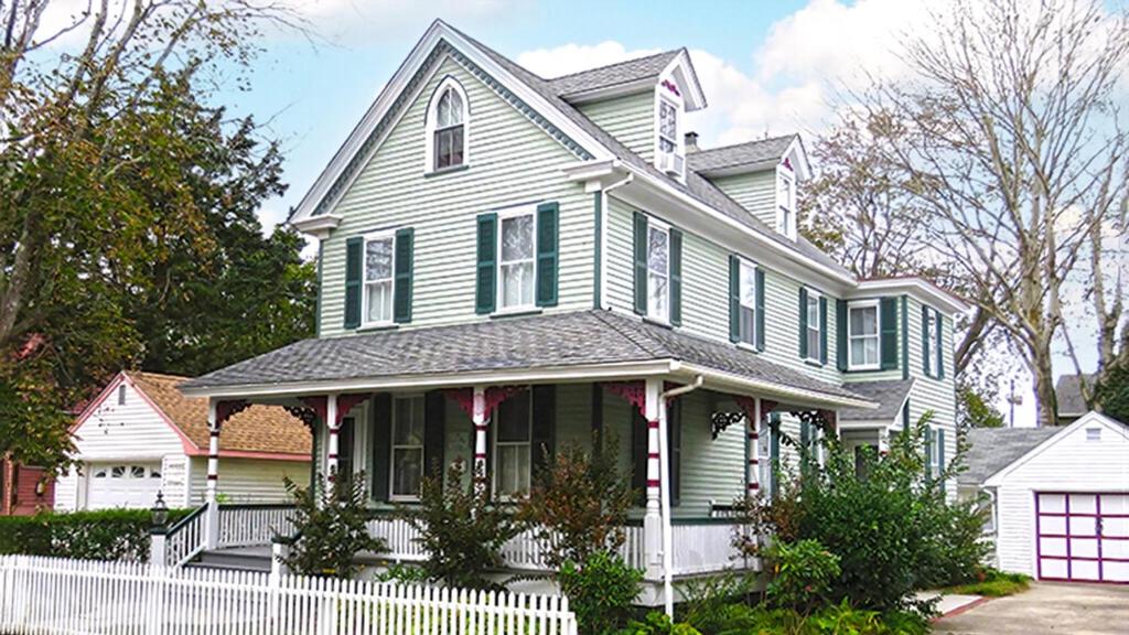 una casa verde con una recinzione bianca davanti di The Windsor Cottage a Cape May