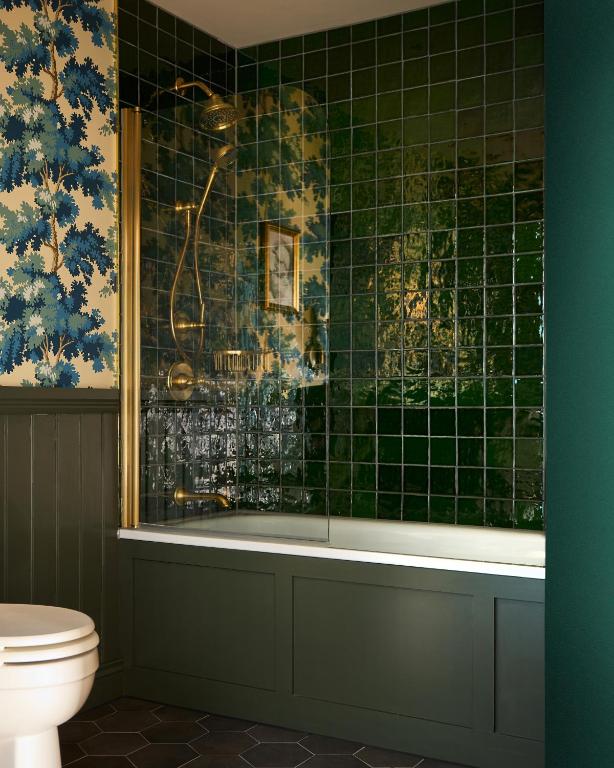 a bathroom with a green tiled tub and a toilet at Portrush Adelphi in Portrush