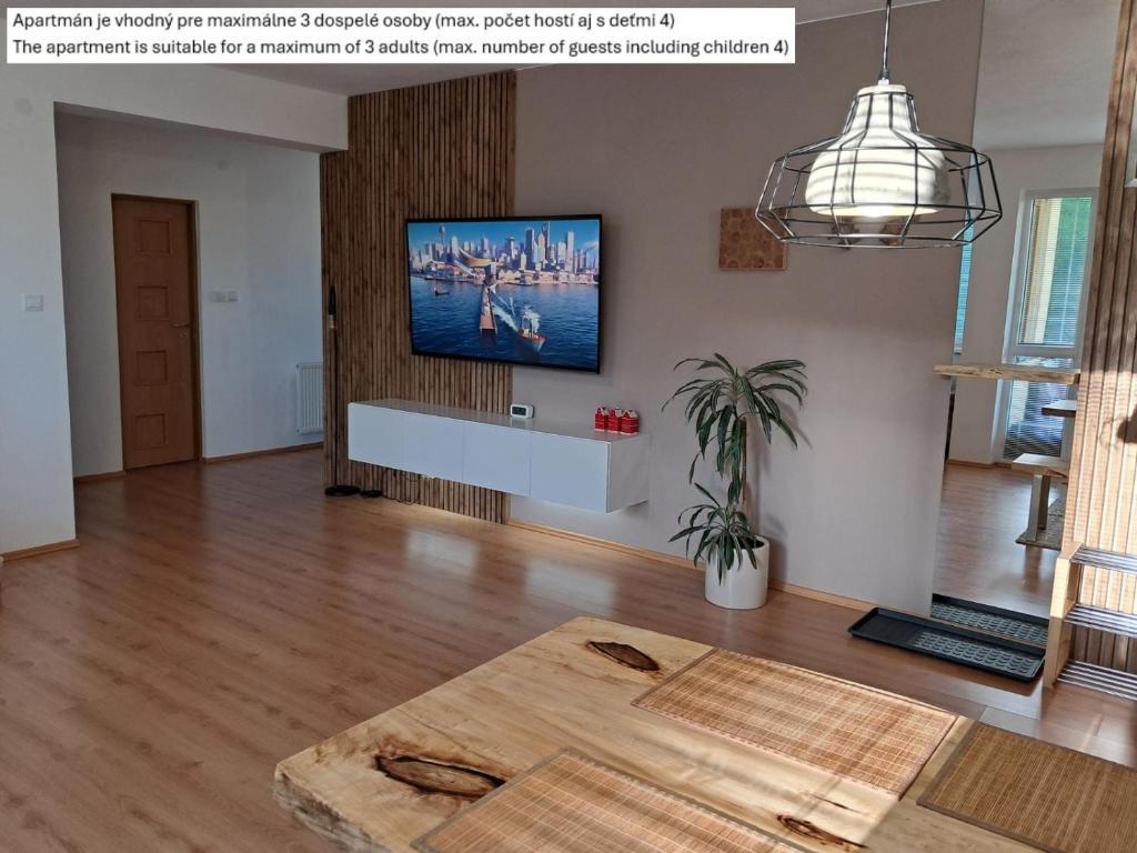 Una sala de estar con una mesa y un televisor en la pared. en Apartment SKI-BIKE-HIKE 2, Vyšné Ružbachy, en Vyšné Ružbachy