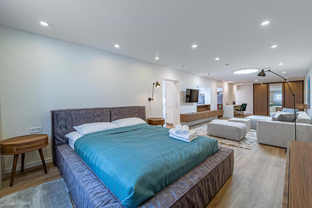 a bedroom with a large bed and a living room at Symphony Apartment with free parking in Kaunas