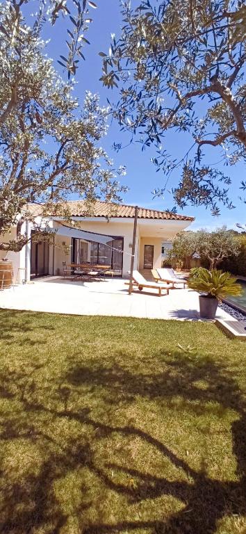 une maison avec une grande cour avec une pelouse dans l'établissement Le Pérignan maison 3 chambres piscine, à Fleury