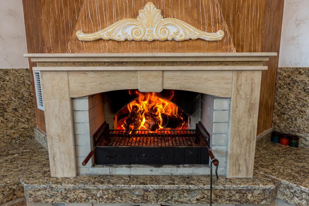 a stone fireplace with a fire in it at Hotel Kristal in Dospat