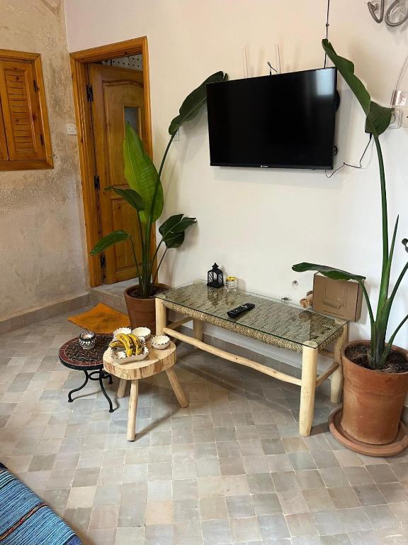 a living room with a table and a tv on a wall at Taghazout Gem - 2BR, Fast Wi-Fi in Agadir