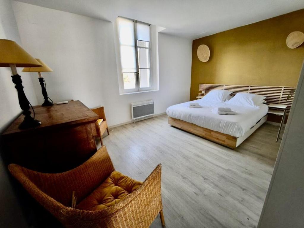a bedroom with a bed and a chair and a desk at La Maison de l'Aqueduc in Cournanel