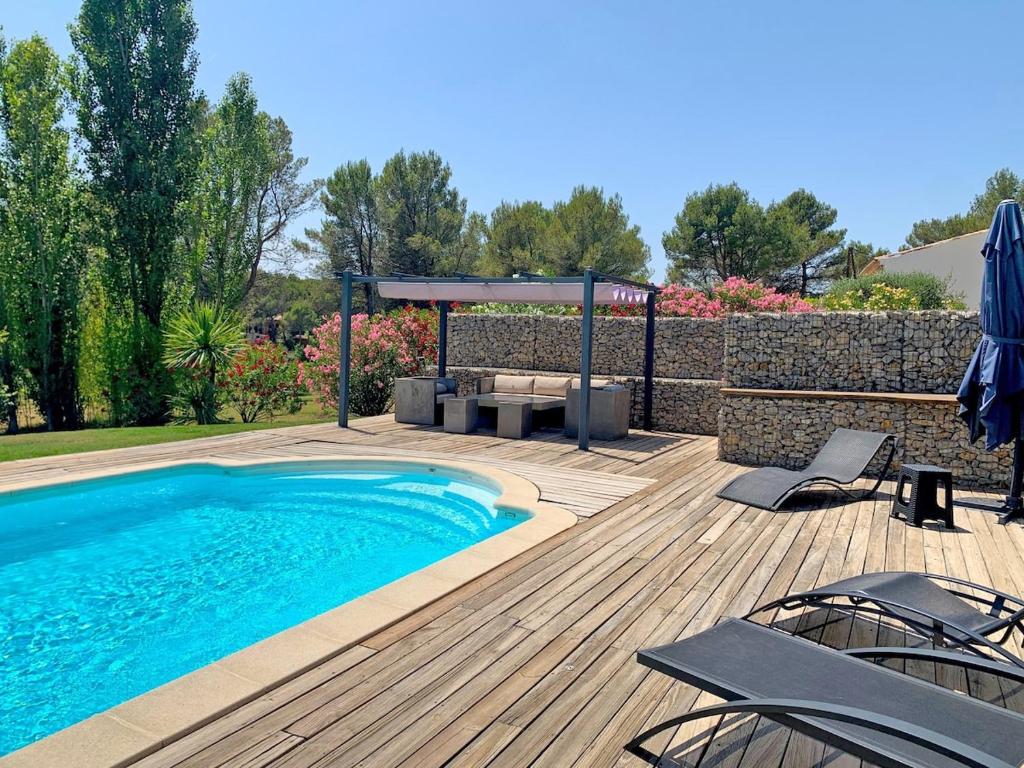 une piscine sur une terrasse en bois avec des chaises et un gazebo dans l'établissement Villa au coeur de la Provence, à Lambesc