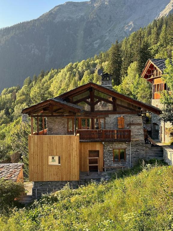 une maison au sommet d'une colline avec une montagne dans l'établissement Chalet authentique avec jacuzzi proche de Val d'Isère, à Sainte-Foy-Tarentaise