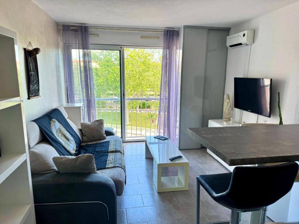 un salon avec un canapé et une grande fenêtre dans l'établissement Studio idéal couple, au Cap d'Agde