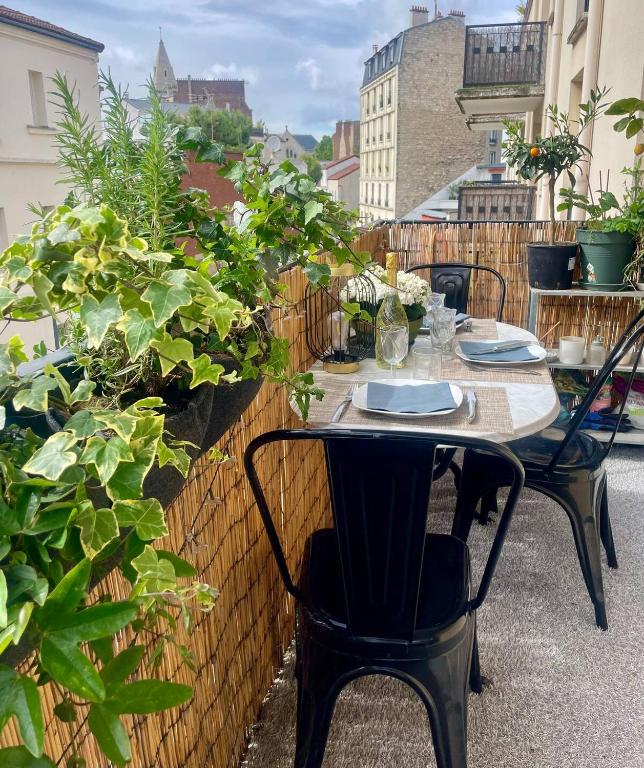 d'une table et de chaises sur un balcon orné de plantes. dans l'établissement Charmant 2p terrasse Paris près sites JO, dont 3 en métro direct Free WIFI, à Paris