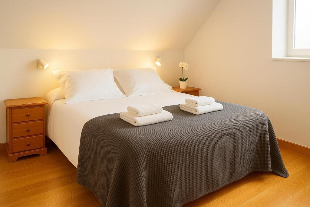 a bedroom with a bed with two towels on it at Cerca de Santander La Llosa de Muriedas en Urbanización in Camargo
