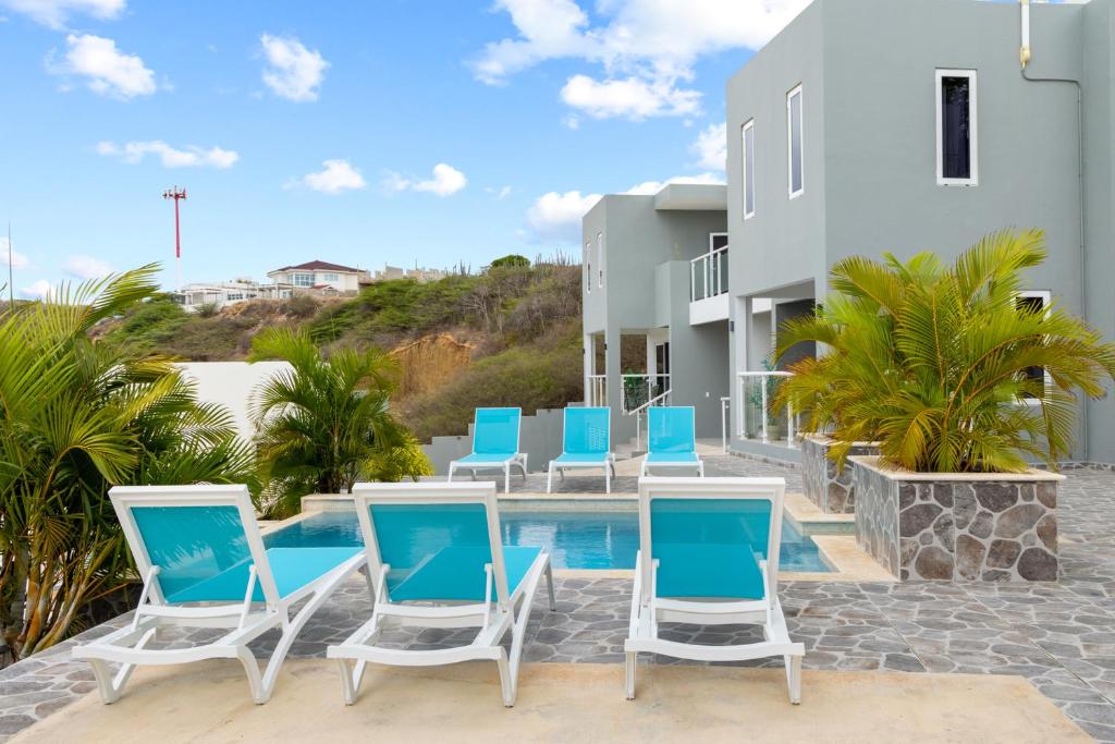 a group of blue and white chairs next to a swimming pool at Casa Tortuga, Relaxed house for Family & Friends on Grote Berg, Curaçao in Grote Berg