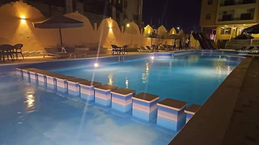 a swimming pool at night with chairs around it at كومباوند فوكس هاوس in Hurghada