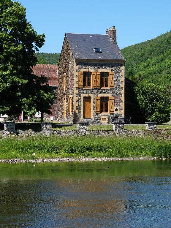 une vieille maison en pierre à côté d'une nappe d'eau dans l'établissement La Malavisée, à Tournavaux