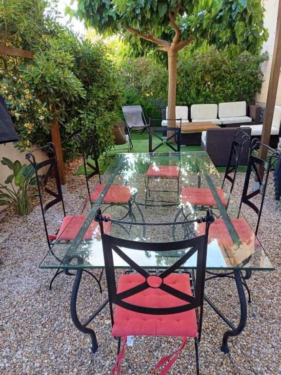 une table en verre avec des chaises rouges et une table en verre et des chaises dans l'établissement T3 Rez de jardin SANARY CENTRE, à Sanary-sur-Mer