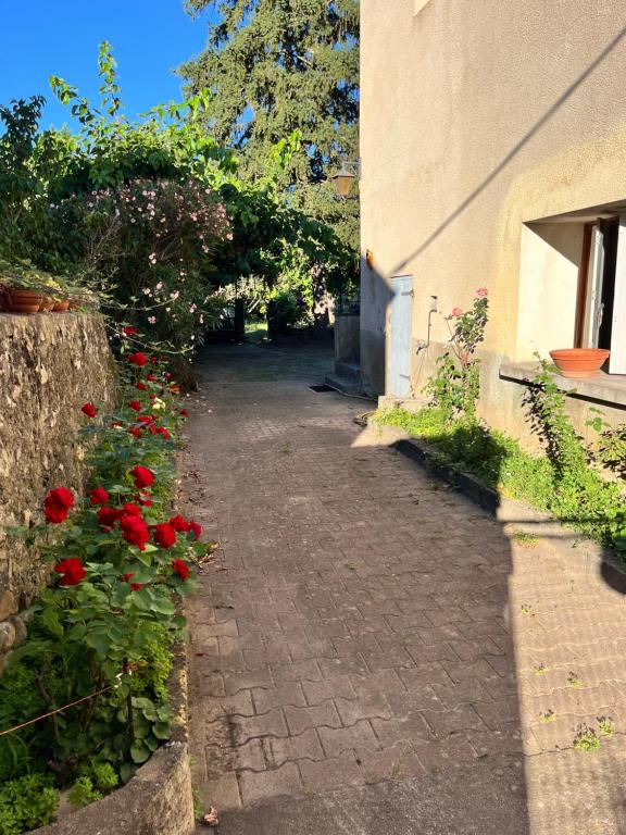 un chemin avec des fleurs rouges à côté d'un bâtiment dans l'établissement maison au coeur du village, à Ruoms