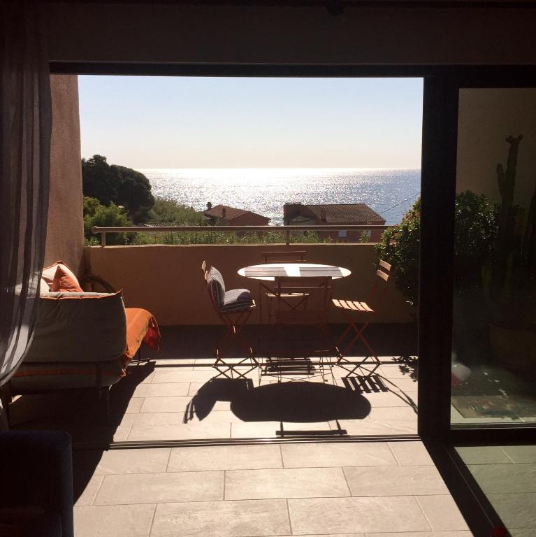 un balcon avec une table et une vue sur l'océan dans l'établissement Cap Nioulargo, à Ramatuelle