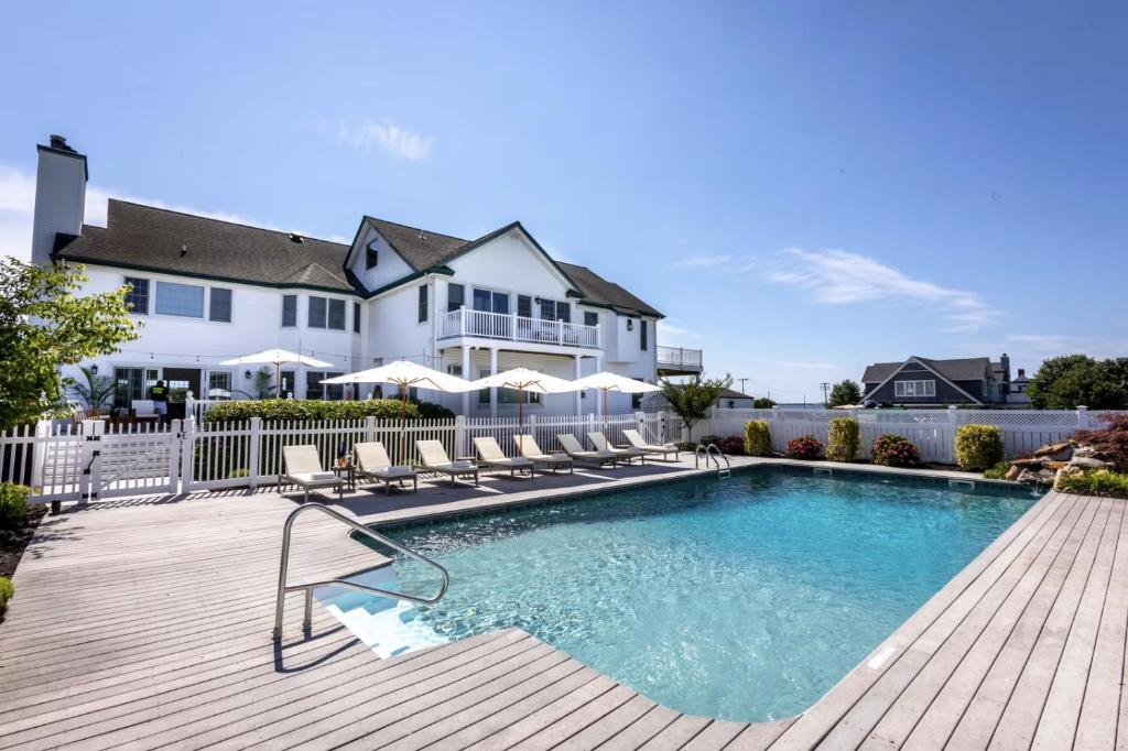 a swimming pool with chairs and a house at The Watermark Hamptons in Eastport
