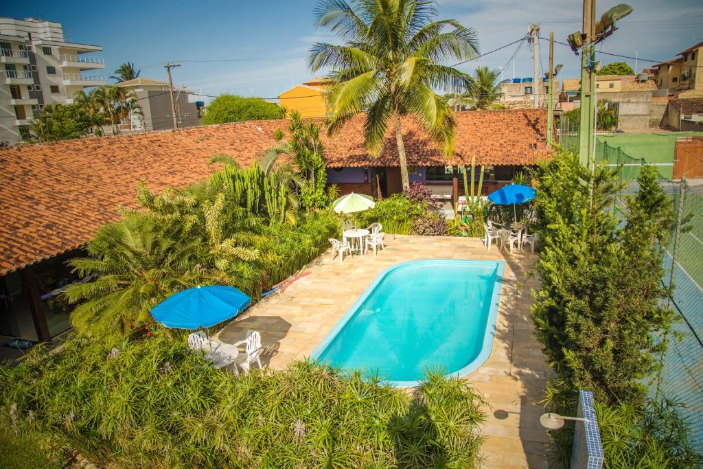 una vista sul soffitto di una piscina con sedie e ombrelloni di Pousada Ocean Blue com Quadra de Beach Tenis a Rio das Ostras