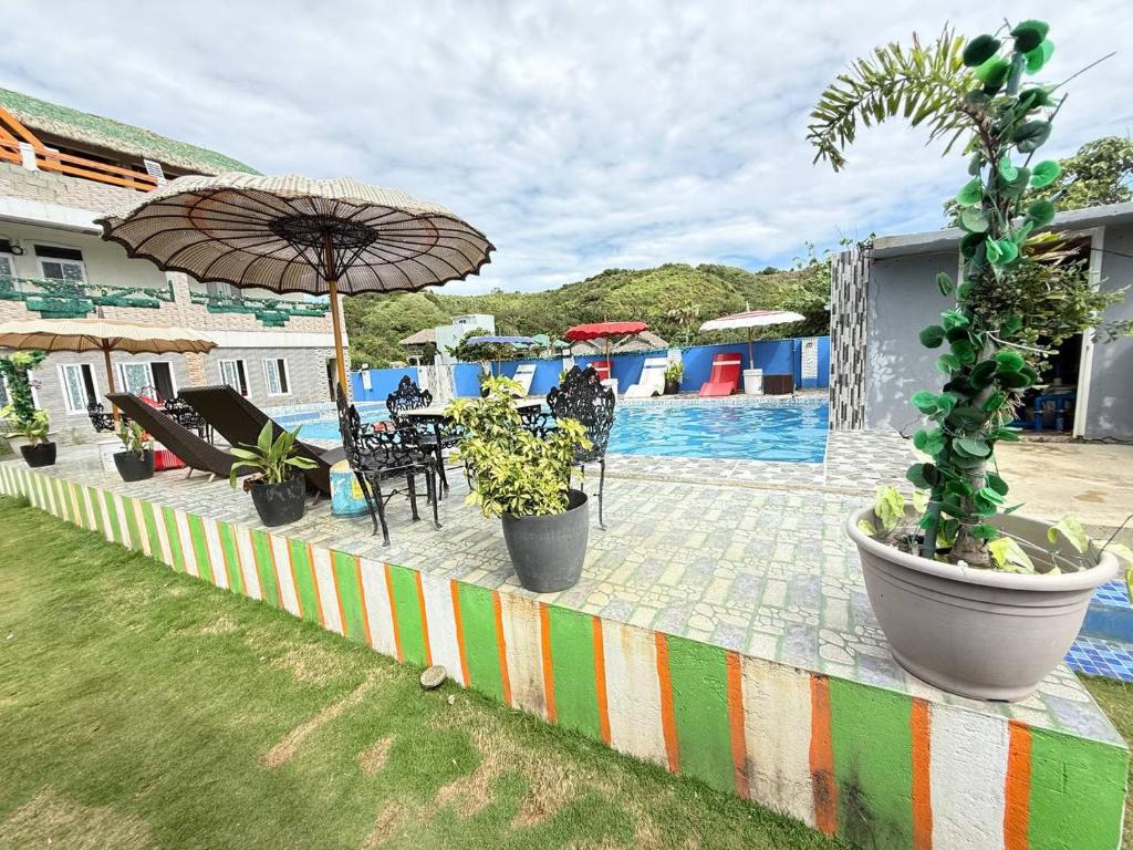 a patio with chairs and an umbrella next to a pool at Mountain cove villa in Pagudpud
