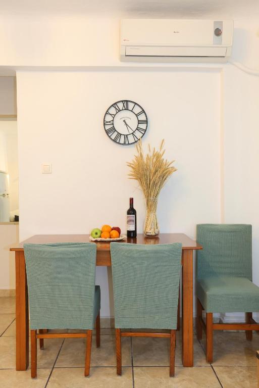 a dining room table with chairs and a clock on the wall at Terra Olivae Syros in Ermoupoli