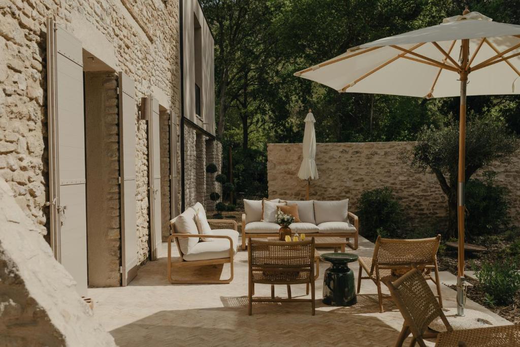 un patio avec des chaises et une table avec un parasol dans l'établissement Provençal Mansion In The Heart Of Fontaine De Vaucluse, à Fontaine-de-Vaucluse