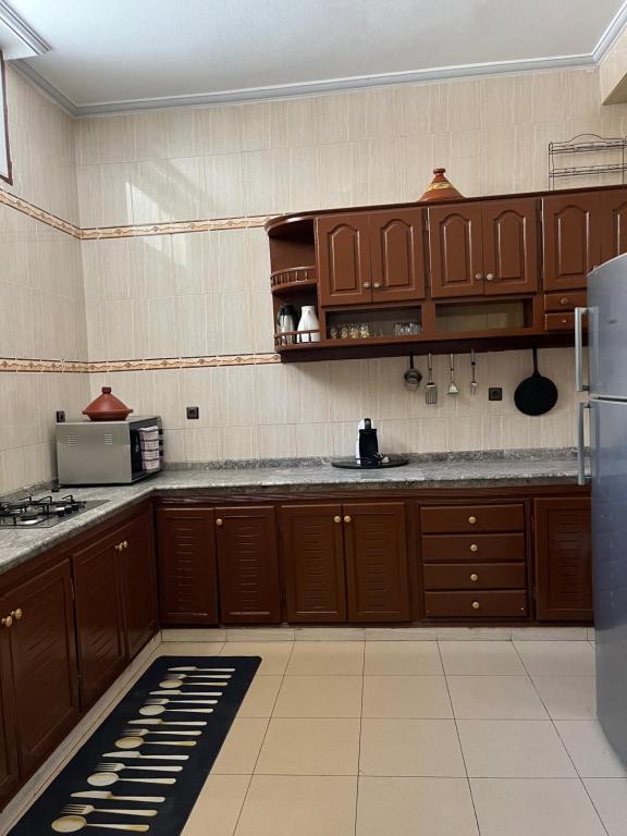 een keuken met houten kasten en een koelkast bij Al houceima in Al Hoceïma