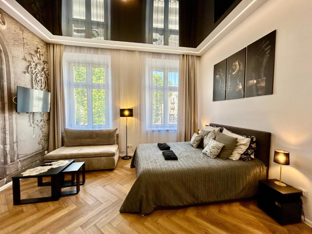 a bedroom with a bed and a couch and windows at Sky Mirror jacuzzi in Kraków