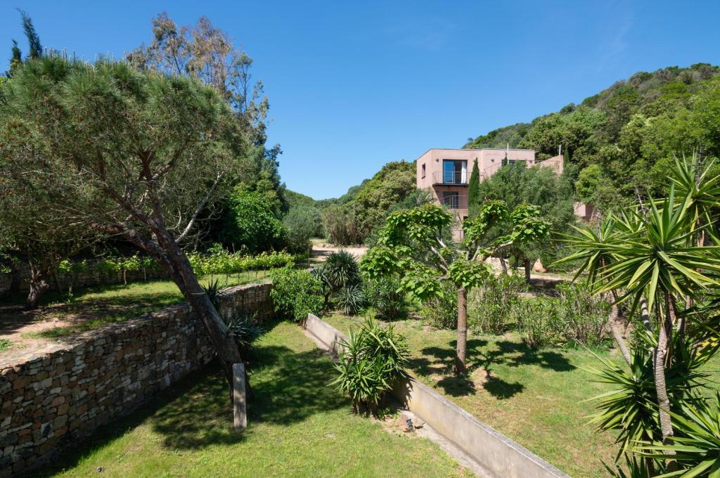 un jardin avec des arbres et un bâtiment en arrière-plan dans l'établissement Villa Vallée Longa - Tarra Zuria, à Bonifacio