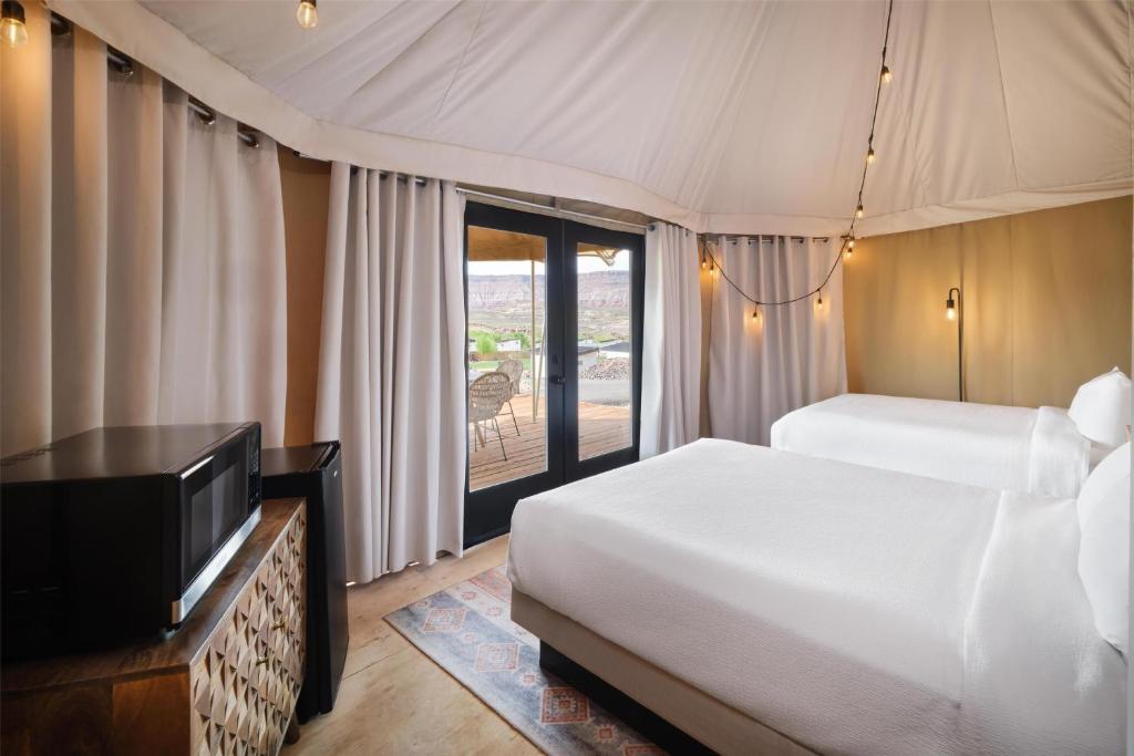 a bedroom with a bed and a flat screen tv at Zion Wildflower Resort in Virgin