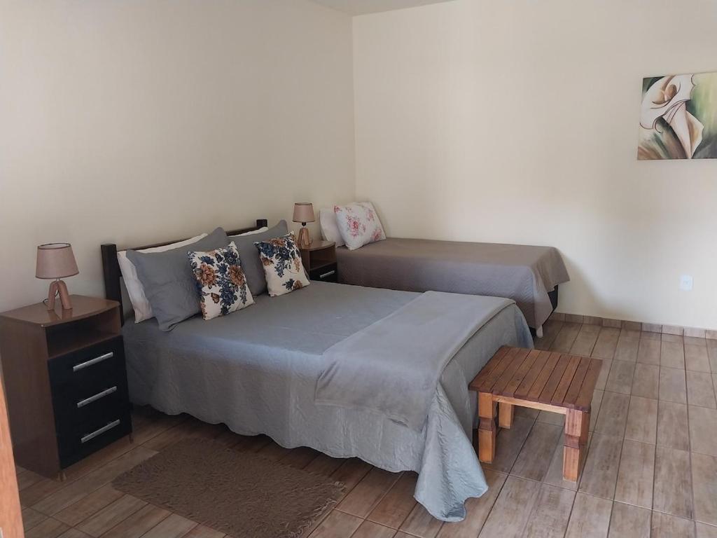 a bedroom with two beds and a night stand and a table at Hospedagem Fernandes Cunha, SP in Cunha