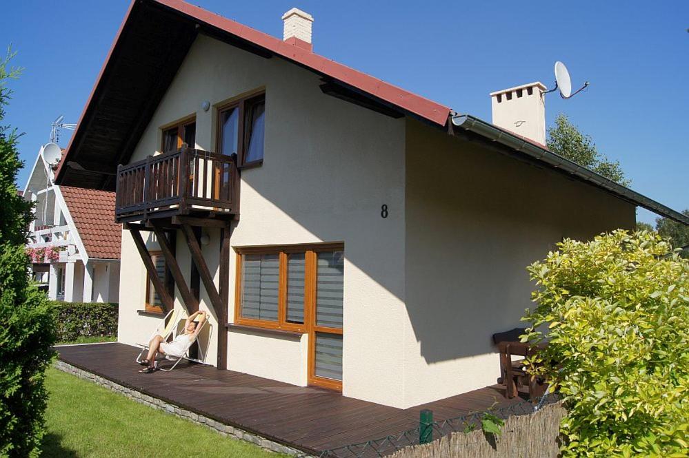 Un perro sentado en una terraza frente a una casa. en Dom letniskowy Kasia Rowy, en Rowy