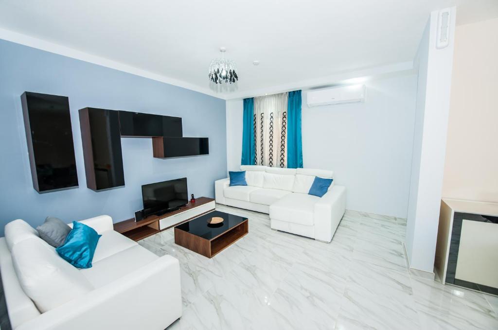 a living room with two white couches and a tv at The Waves holiday apartment in Marsaxlokk