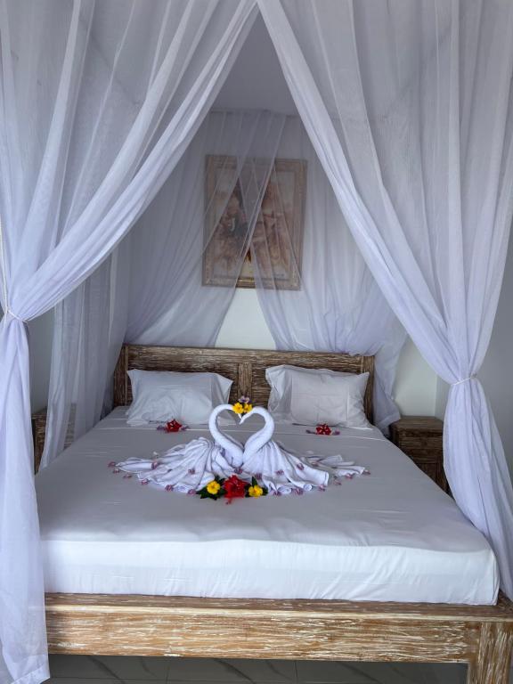 1 dormitorio con 1 cama con dosel blanco en LAHANGAN SWEET cottages, en Culik