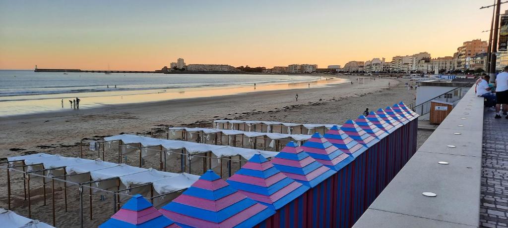 une plage avec une rangée de barrières bleues et blanches dans l'établissement Océan, à Les Sables-dʼOlonne