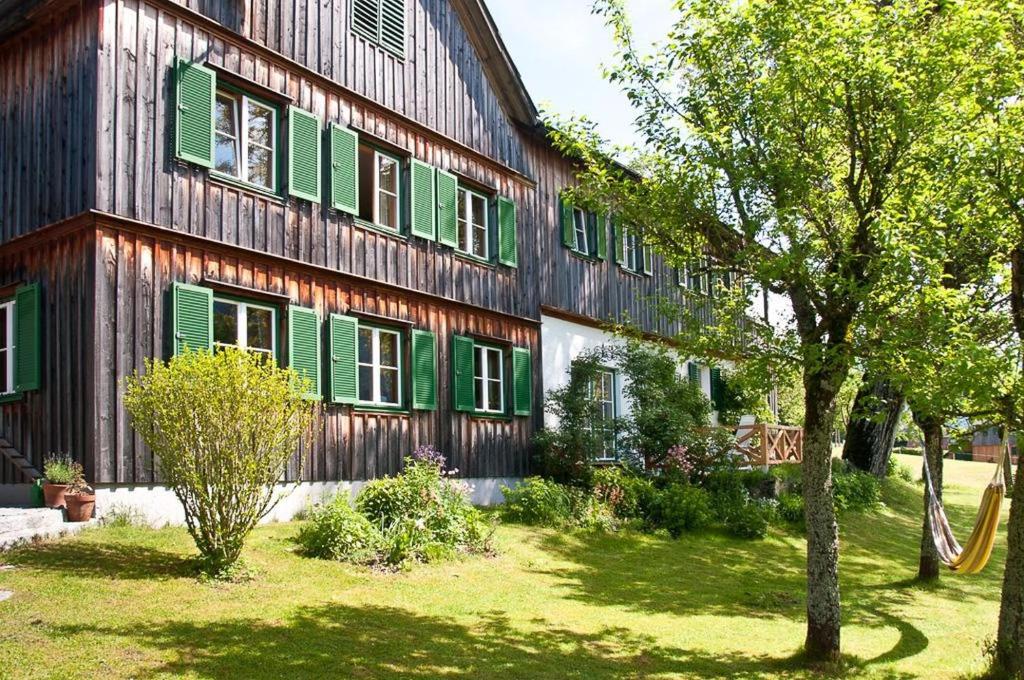 a large wooden building with green shutters on it at Hütterhof in Grundlsee