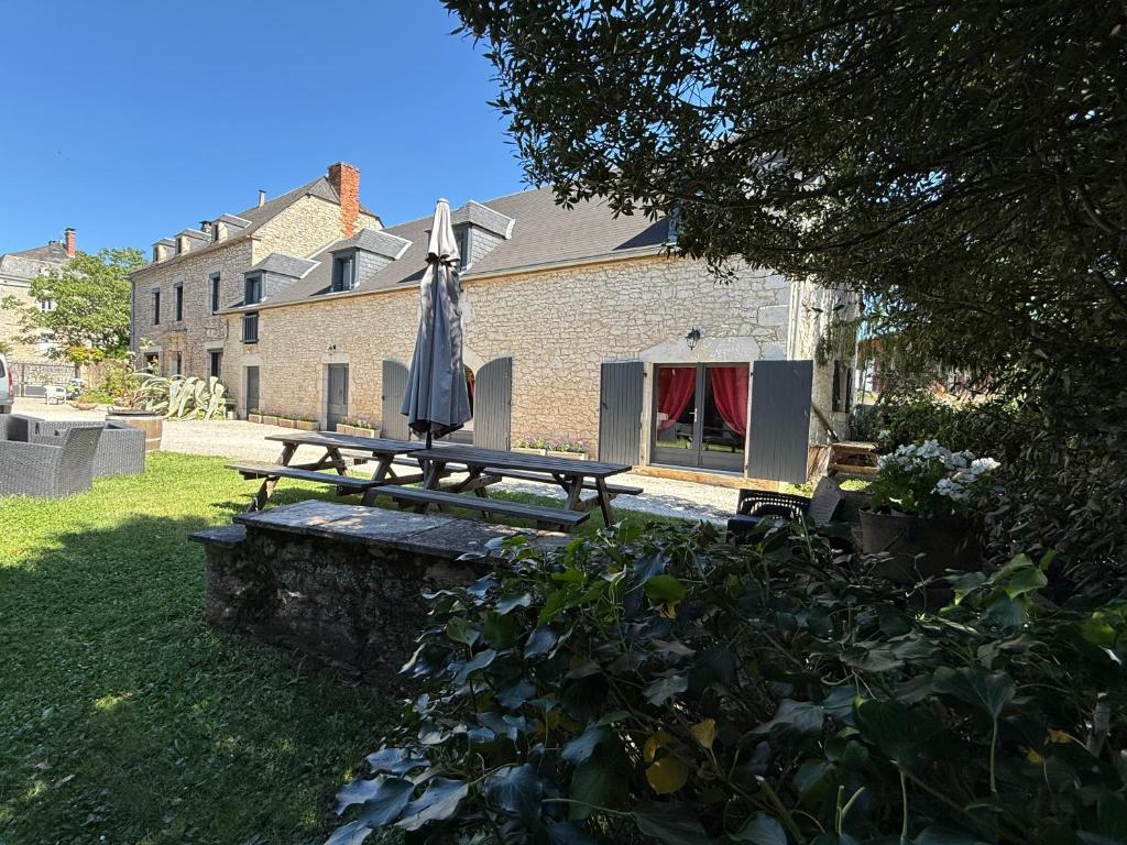 a picnic table with an umbrella in a yard at Grange authentique en Quercy in Pinsac