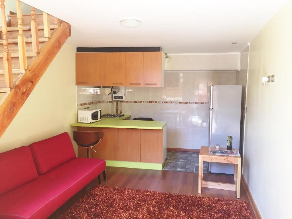 uma sala de estar com um sofá vermelho e uma cozinha em Tribu Malen Apartamentos em Temuco