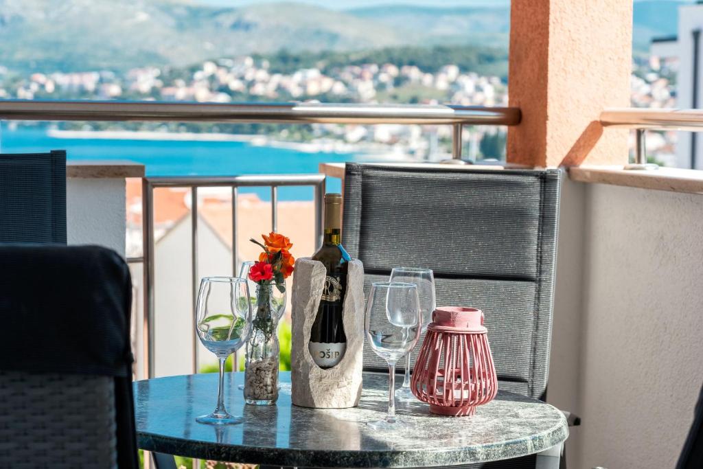 una mesa con botellas de vino y copas en el balcón en Apartman Moje, en Okrug Gornji