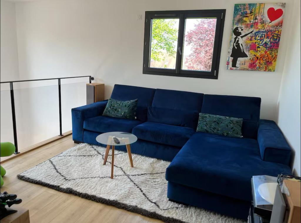 a blue couch in a living room with a window at Loue étage in Saint Pavace