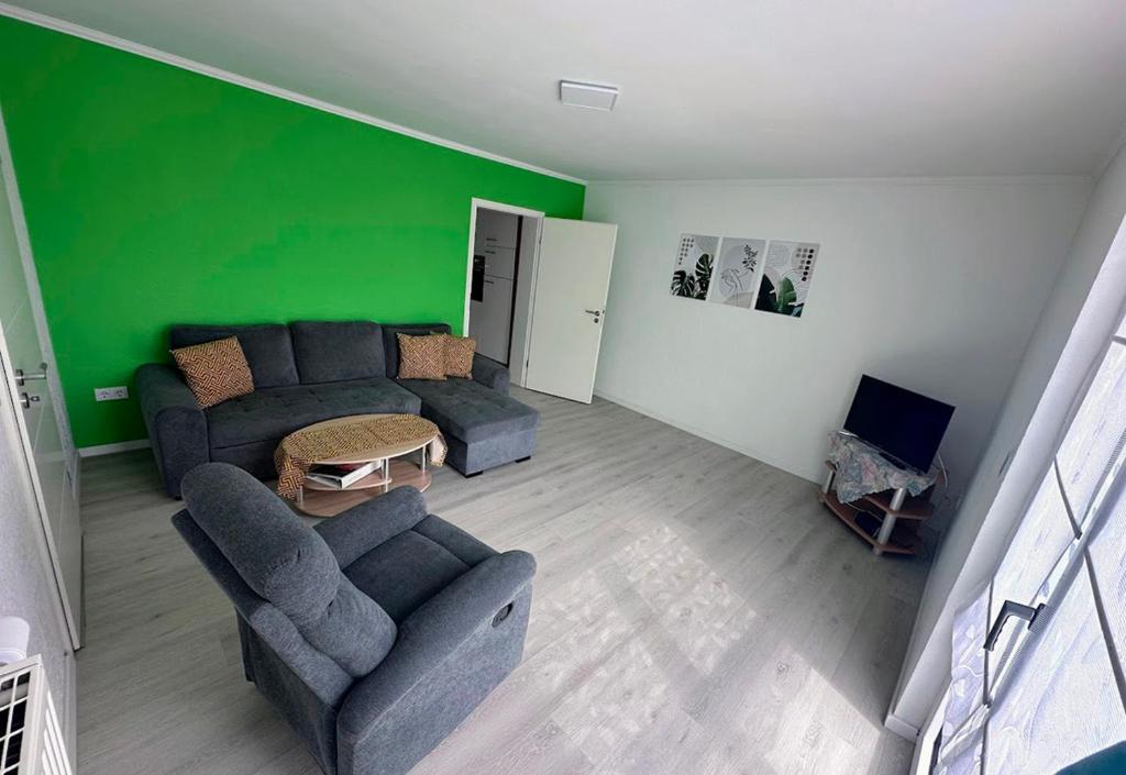 a living room with a couch and a green wall at Ferienwohnung Hochwaldblick 4 in Morbach