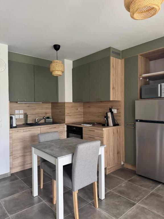 une cuisine avec une table, des chaises et un réfrigérateur dans l'établissement O'petit nid sauge T2 45m place de parking, à Aix-les-Bains